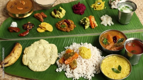 Traditional Onam sadhya rice Sambar, Rasam, parippu dal curry ghee Pappadom Payasam on banana leaf Onam Vishu Pongal Diwali festival vegetarian food Kerala Tamil Nadu South India. 4k video footage photo