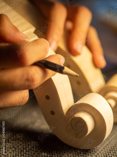 Fotografie luthier artisan maker sculpting and carving violin scroll and neck with chisel
