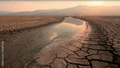 Landscape of river drying with dry cracked earth at sunset metaphor climate change, Global warming and Drought on summer, Heat wave and hot temperature impact to water source. photo