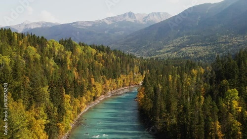astonishing  dolly forwards zoom shot over fraser river in Mount Robson Provincial Park in British Columbia in Canada on a sunny day surrounded by forest with yellow and green trees and mountain peaks photo