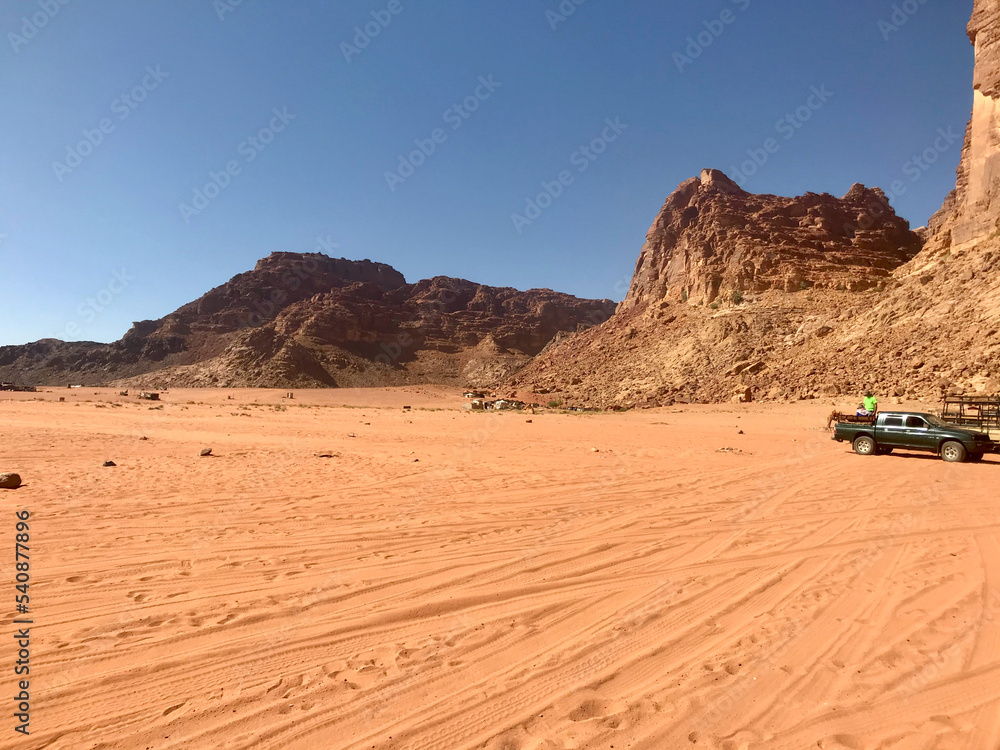 Wadi Rum, Jordan, November 2019 - A close up of a desert field with a mountain in the background Wadi Rum, Jordan, November 2019 - A close up of a desert field with a mountain in the background