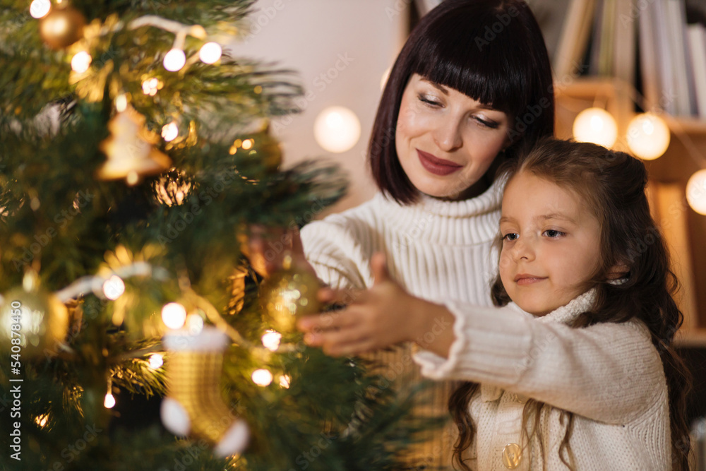 Mother and daughter holding decoration for Christmas tree. Stylish interior of a children's room. Scandinavian eco-style decor. New Year celebration. Christmas eve. Support joint time forwarding. love Mother and daughter holding decoration for Christmas tree. Stylish interior of a children's room. Scandinavian eco-style decor. New Year celebration. Christmas eve. Support joint time forwarding. love