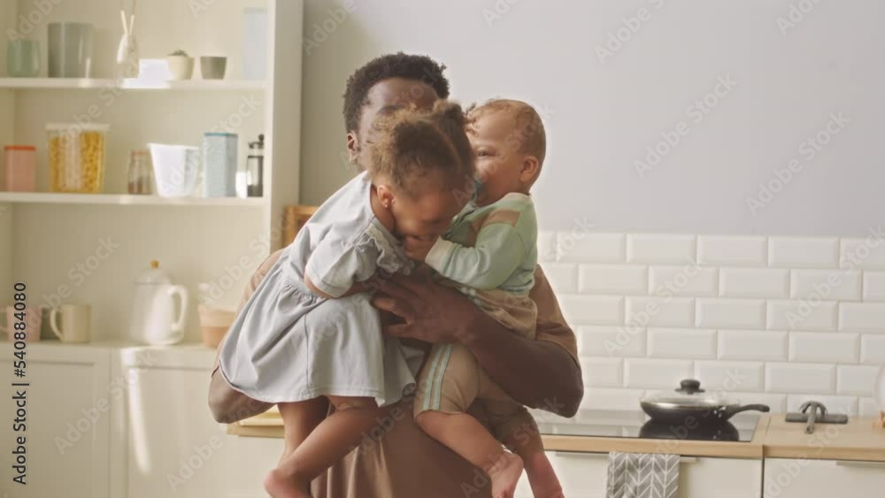 African American man holding his toddler daughter and baby son on arms playing and having fun together African American man holding his toddler daughter and baby son on arms playing and having fun together