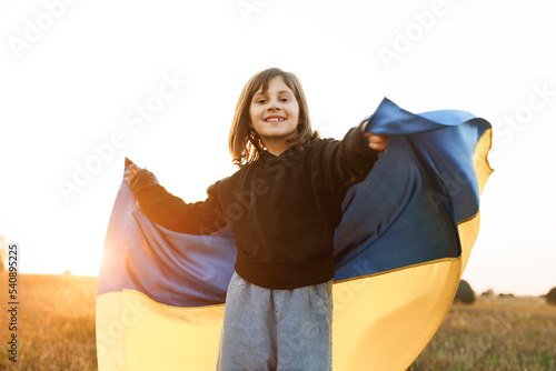 Portrait of Ukrainian child girl in embroidered shirt vyshyvanka with yellow and blue flag of Ukraine in field. Ukraines Independence Flag Day. Constitution day. Flag symbols of Ukraine. Kiev day. photo