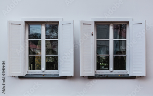 2 okna z białymi framugami na białej ścianie. 