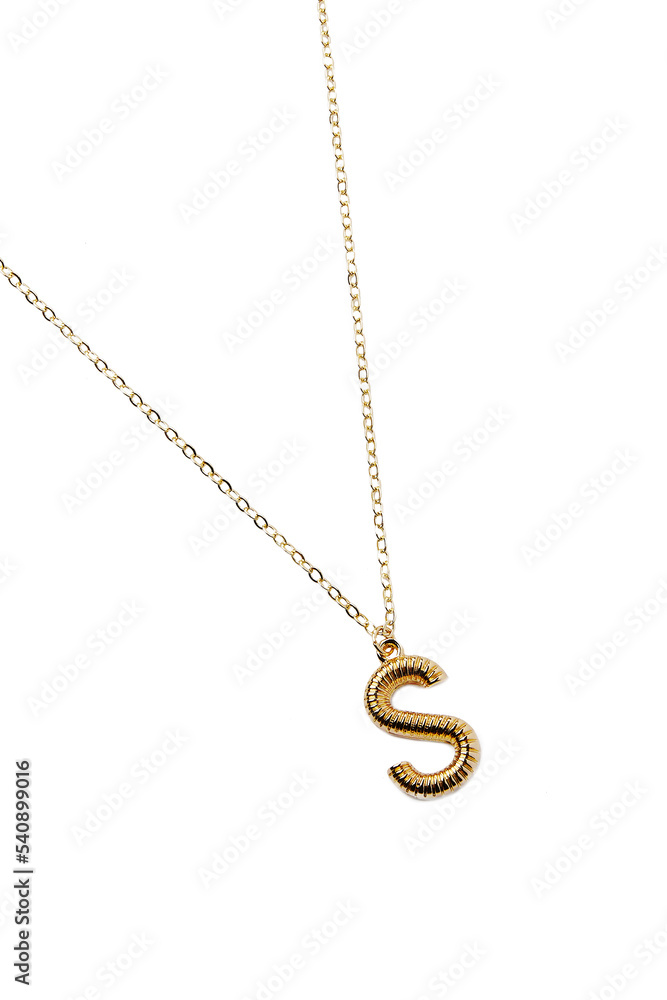 Detail shot of a metal golden necklace made out of a chain with a dangling pendant with a letter Detail shot of a metal golden necklace made out of a chain with a dangling pendant with a letter