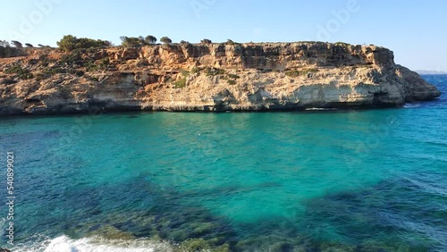 View of turquoise crystal clear sea with swinging waves and rocky coast in Mallorca island, Spain.