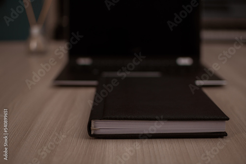 
The notepad lies in front of the laptop in the home office. Focus at the bottom of the notepad