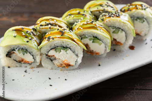 green dragon sushi roll. japanese food over white plate. Sushi roll with salmon, cream cheese and avocado. Japan restaurant menu.