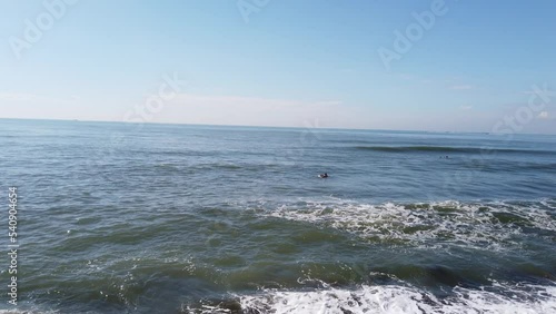 Surfers Taking a Wild Wave in High Tide East Bali Indonesia Dirty Water, Ketewel Beach, 60 Fps near the Black Stones, Clear Blue Sky photo