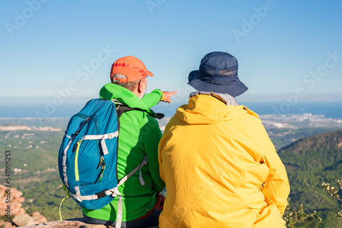 Two hikers relax on top of a mountain with a great view