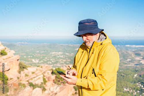 elderly man using phone to check map during hiking trip