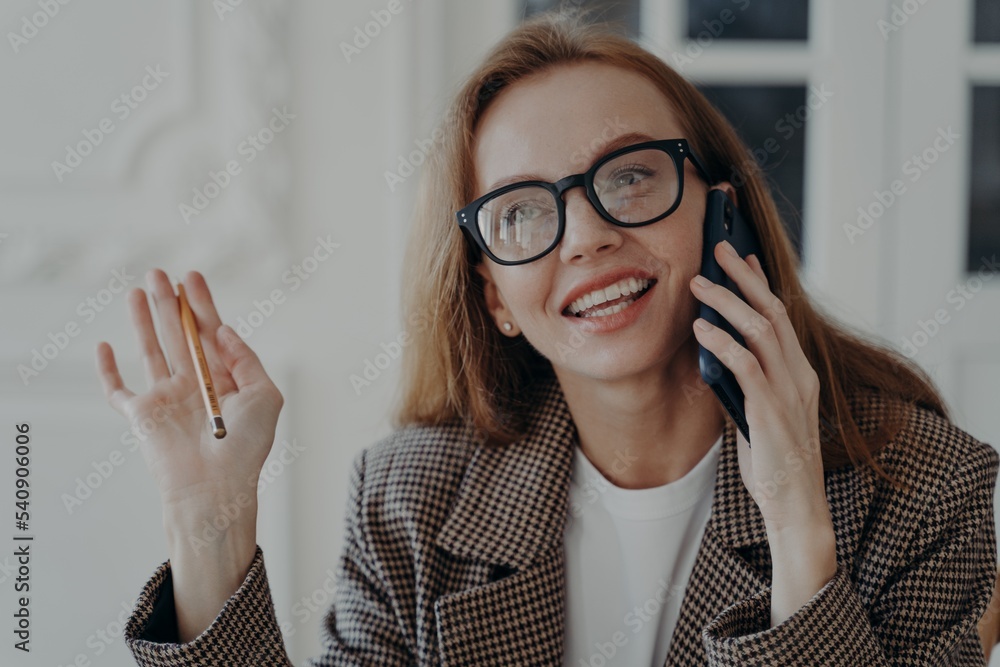 Smiling businesswoman in glasses answers call, talks on phone enjoying corporate mobile conversation Smiling businesswoman in glasses answers call, talks on phone enjoying corporate mobile conversation