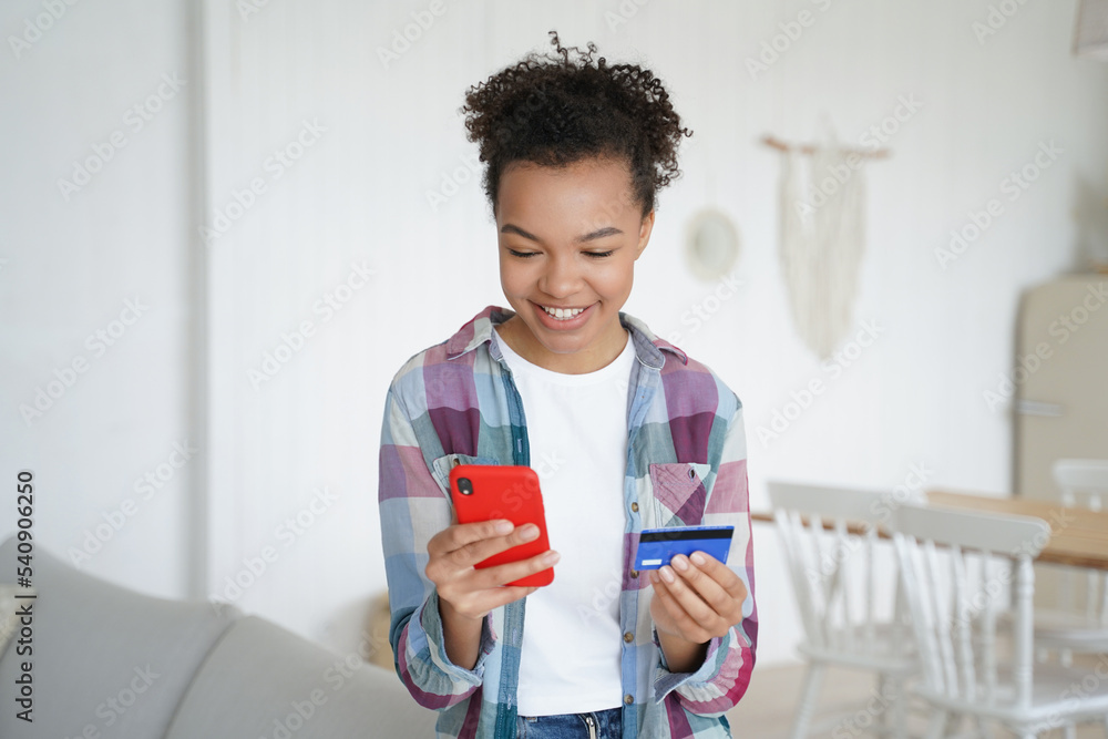 Mixed race young girl holds banking credit card pay purchase online using e-bank phone apps at home Mixed race young girl holds banking credit card pay purchase online using e-bank phone apps at home