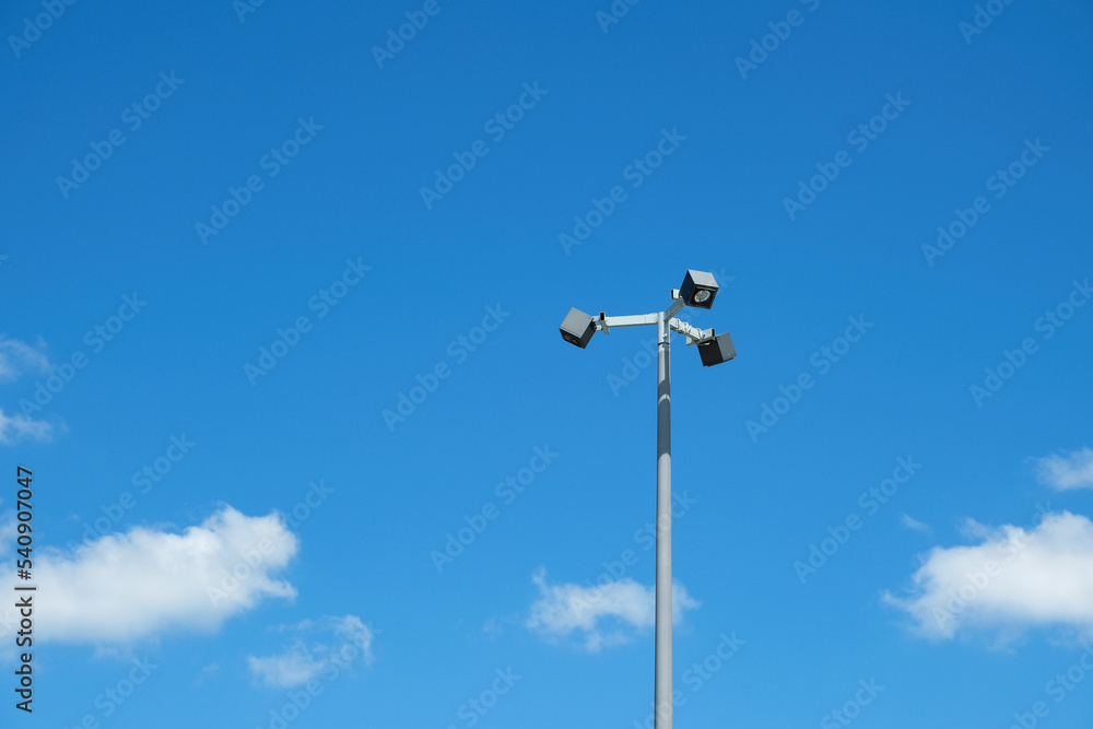Modern metal lamppost of street lighting on a background of blue sky with white clouds. Design element, copy space