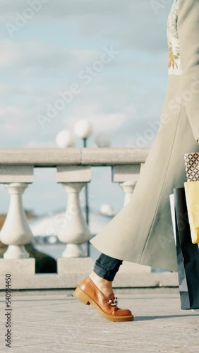 Young attractive woman walks with shopping bags in the old city. Female in coat and beret walking in autumn sunny day. Glamour blond lady.