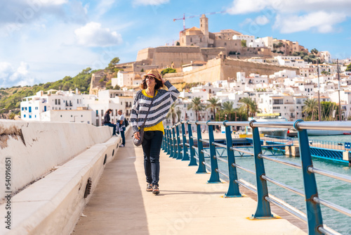 Young woman with hat visiting coastal Ibiza town on vacation from Al Faro, Balearic Islands