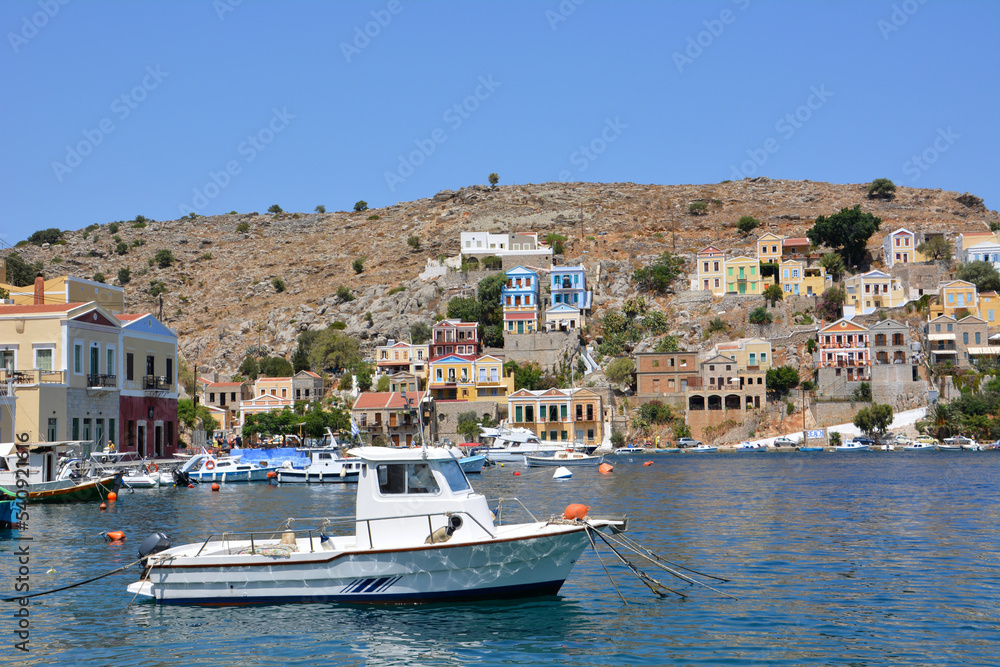 white boat in port of greek island Symi with waterfront on background