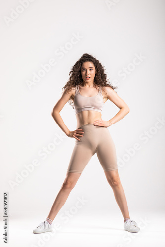 Full body of young cheerful smiling woman in sports wear, isolated over white background