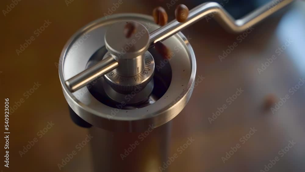 Close up of barista pours coffee beans into a Kinu coffee grinder from package in slow motion Close up of barista pours coffee beans into a Kinu coffee grinder from package in slow motion