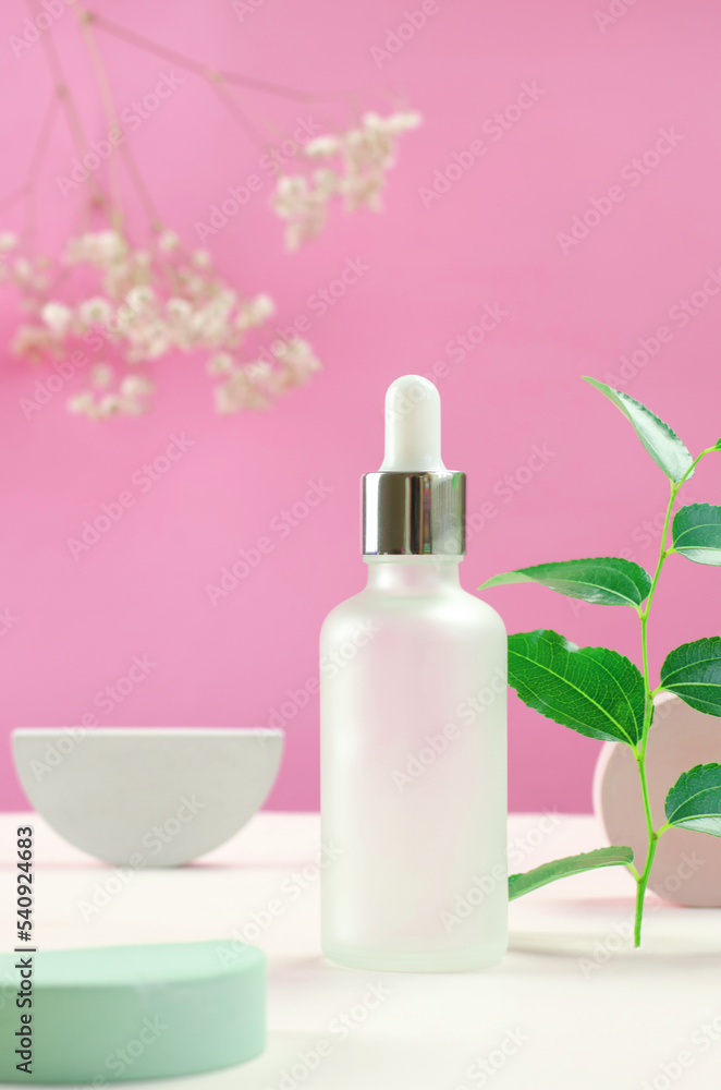 White cosmetic bottle and flowers. Bottle of cosmetic serum or essential oil. Minimal background layout White cosmetic bottle and flowers. Bottle of cosmetic serum or essential oil. Minimal background layout