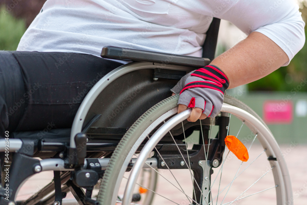 Fototapeta premium Unrecognizable woman with disability sitting in wheelchair in the street close up