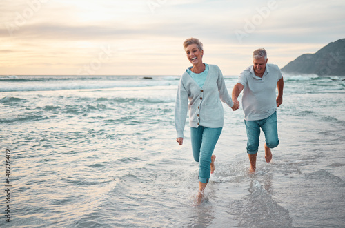 Beach, walking and senior couple holding hands for support, love and care with outdoor wellness, retirement and holiday lifestyle with sunset sky. Elderly people running together in sea ocean water