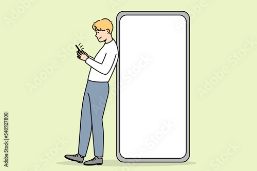 Young man standing near huge smartphone with mockup screen. Guy pose near cellphone with empty blank copy space display. Vector illustration. 