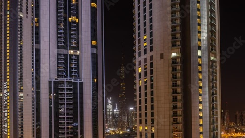 View between tallest skyscrapers in downtown dubai located on bouleward street near shopping mall aerial timelapse during all night. Many lights in windows and illumination turning off photo