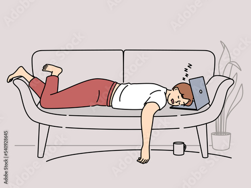Tired man fall asleep on sofa with laptop 