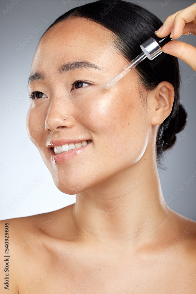 Skincare, face oil and woman with wellness for her skin against a grey studio background. Happy, smile and young Asian model with a facial serum for body healthy, dermatology and a beauty glow