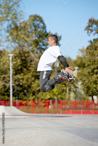 Jump. One man, male roller skater on rollerblades training at modern skate park, outdoors. Action, motion, skills and challenges. Doing different tricks