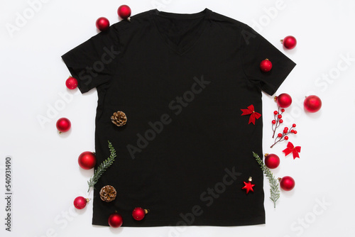 Close up black blank template t shirt with copy space and Christmas Holiday concept. Top view mockup t-shirt and red holidays decorations on white background. Happy New Year accessories. Xmas outfit