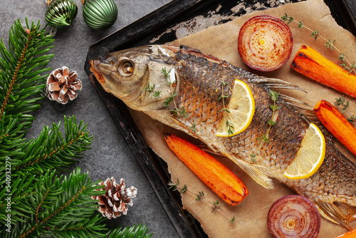 Fried carp whole. Served with lemon and roasted vegetables. Christmas decoration. Czech Traditional Christmas Food. Top view.