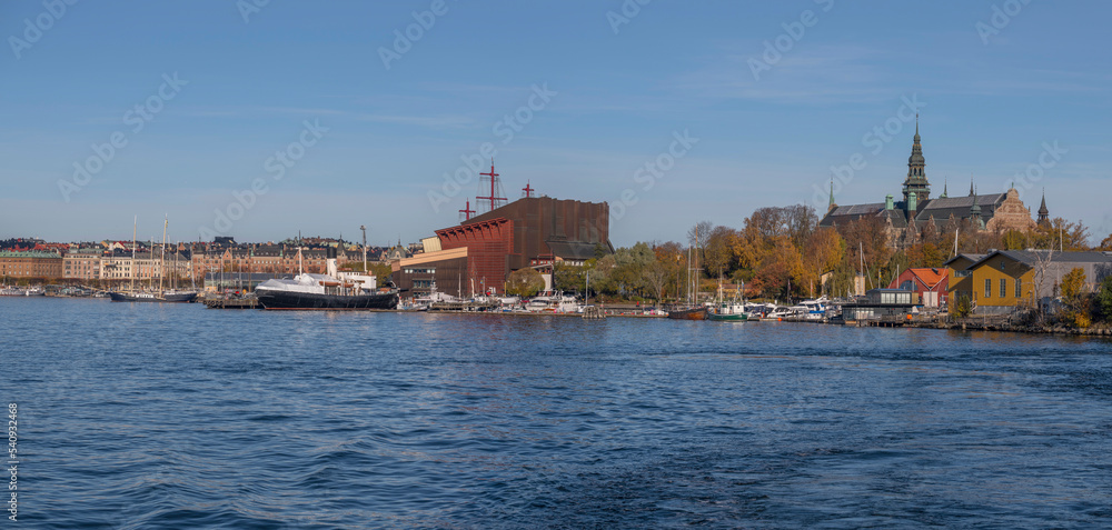 Museum building and boats at the pier Galärvarvet a colorful autumn day in Stockholm