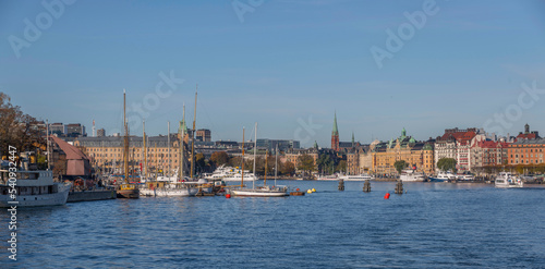 Panorama view, commuting steam boats and harbor ferries in the bay Ladugårdsviken with offices, apartment and hotel buildings a colorful autumn day in Stockholm