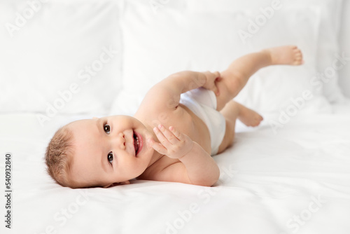 Smiling baby rolling on bed
