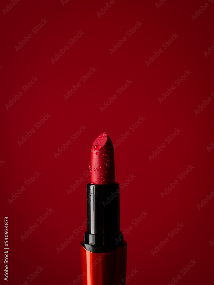 Obraz premium close-up on red lipstick in splashes of water on a red background