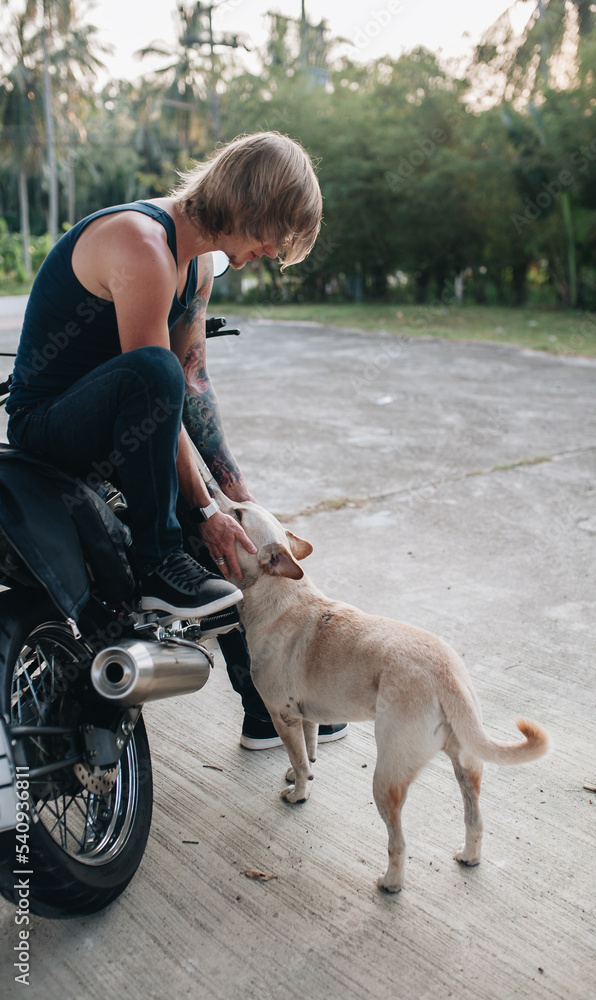 Fair man is sitting on his motorbike with a dog Fair man is sitting on his motorbike with a dog