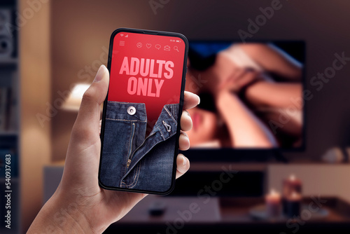Woman watching porn on smartphone and TV photo