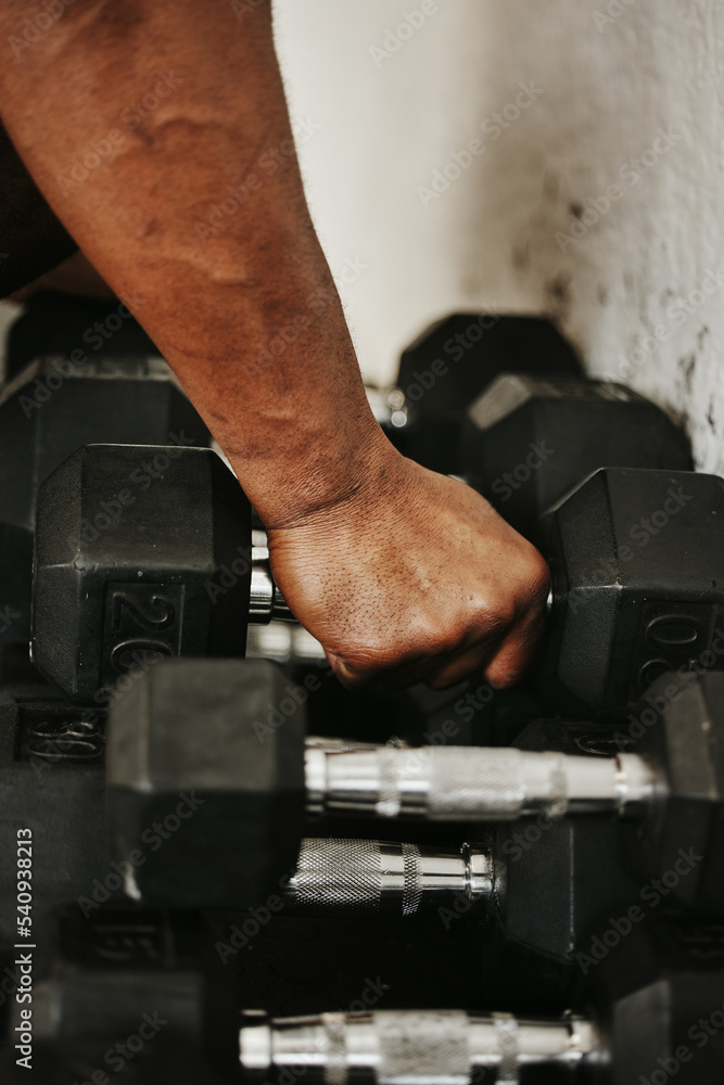 Hand, dumbbell and fitness with a man bodybuilder in a gym for exercise, training or a workout with weights. Hand, dumbbell and fitness with a man bodybuilder in a gym for exercise, training or a workout with weights.