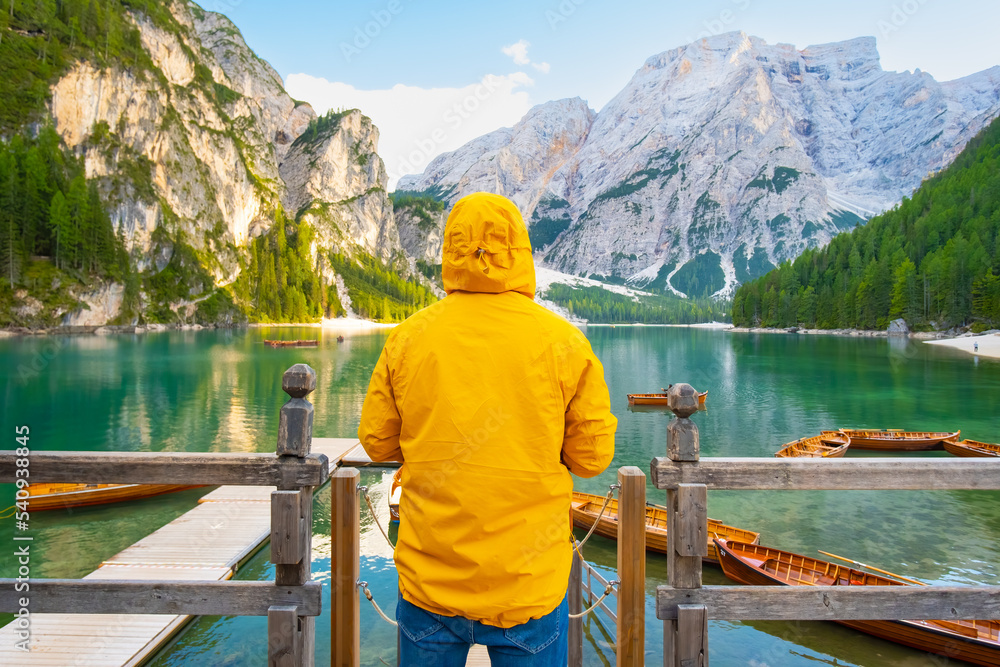 Back view of the man having fun on lake Braies with wooden boats in the Dolomites. 