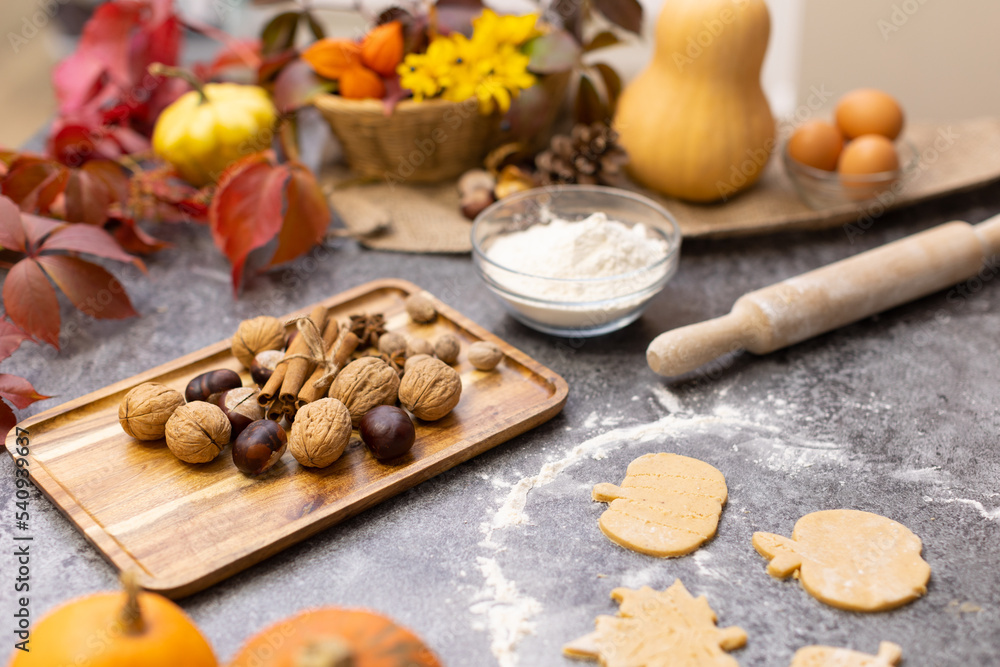 Cooking cookies in the form of leaves on the kitchen table with autumn decor. flat layout. Shortcrust pastry cookies for Thanksgiving and Halloween. wooden rolling pin, flour, dough, leaves, decor.