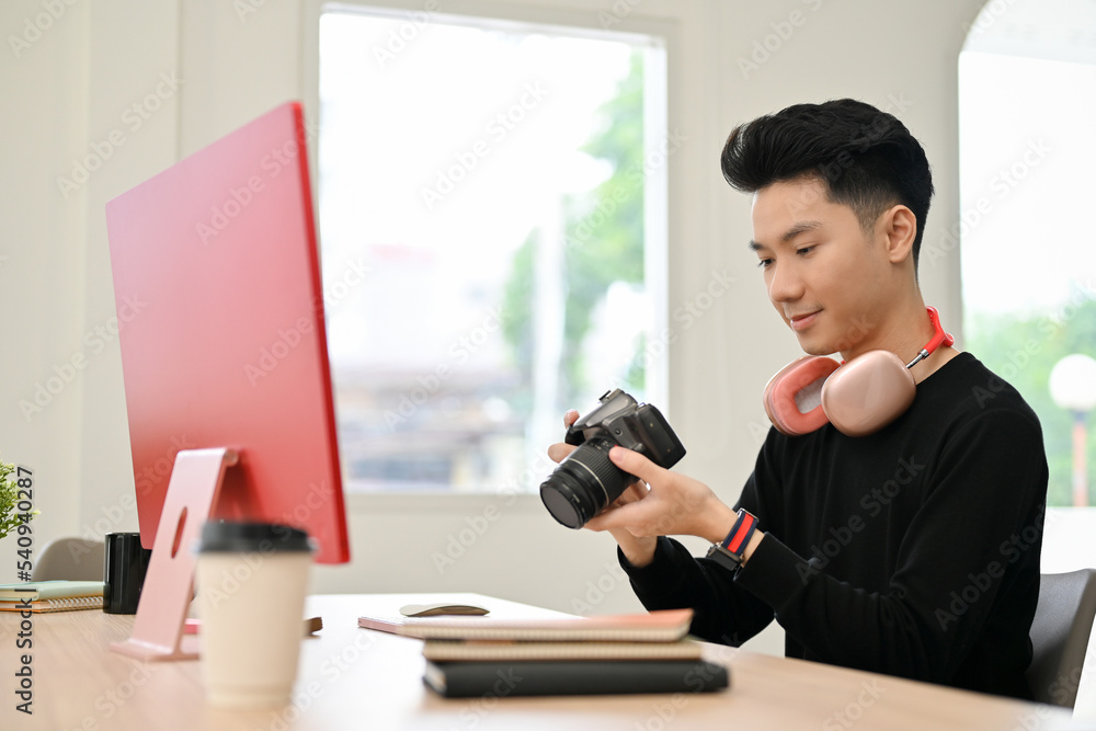 Asian male photographer holding, looking, checking or adjusting a camera before shooting Asian male photographer holding, looking, checking or adjusting a camera before shooting
