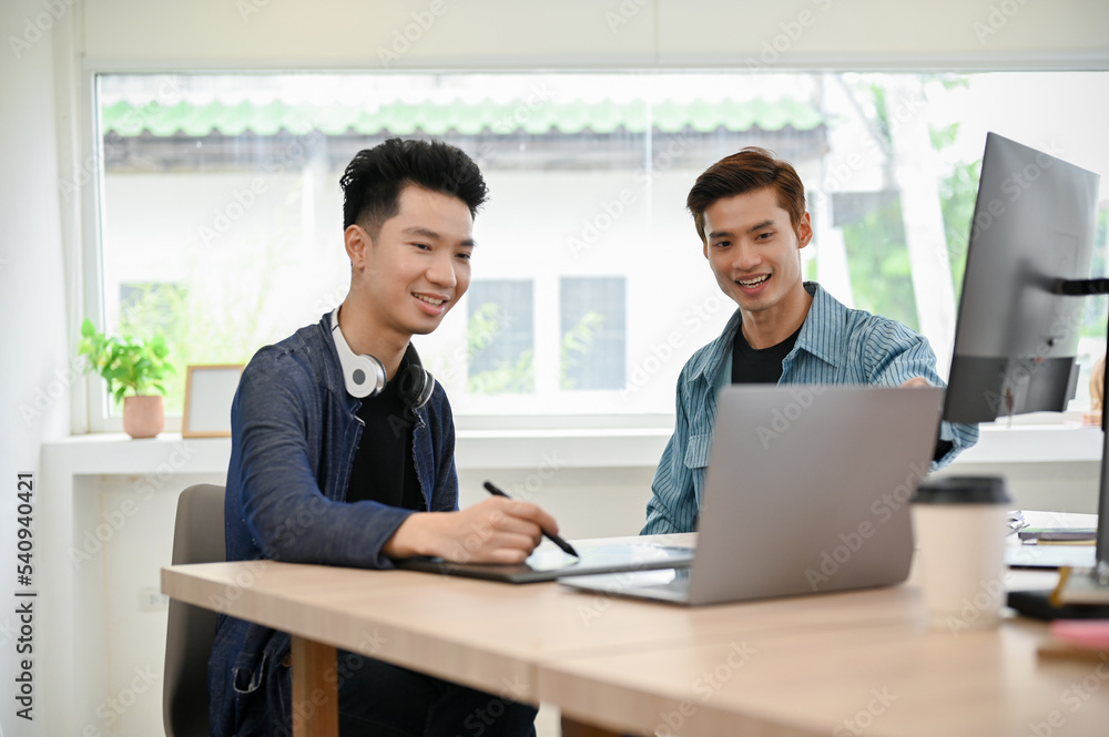 Two Asian male programmers or photo editors working together in the office Two Asian male programmers or photo editors working together in the office