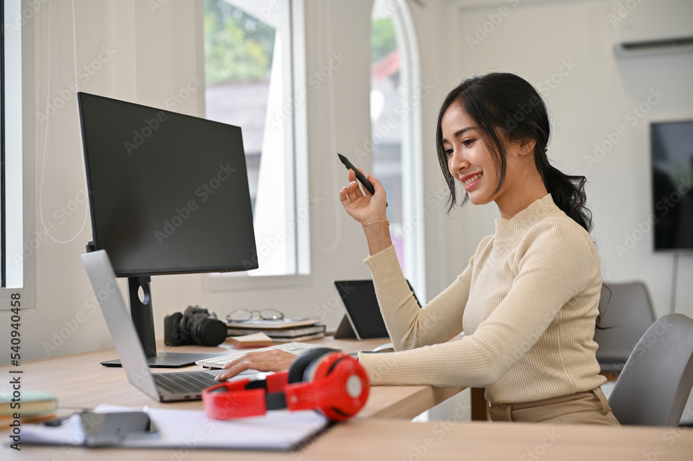 Attractive Asian businesswoman or female graphic designer using laptop computer