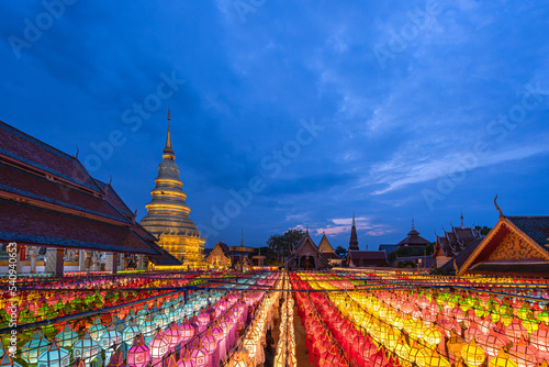 Beautiful gold pagoda and Lantern Lamp light colorful in Loi Krathong Festival hung up on the rail to pray the prosperity at Wat Phra That Hariphunchai, Lamphun, Northern Thailand. © pomphotothailand