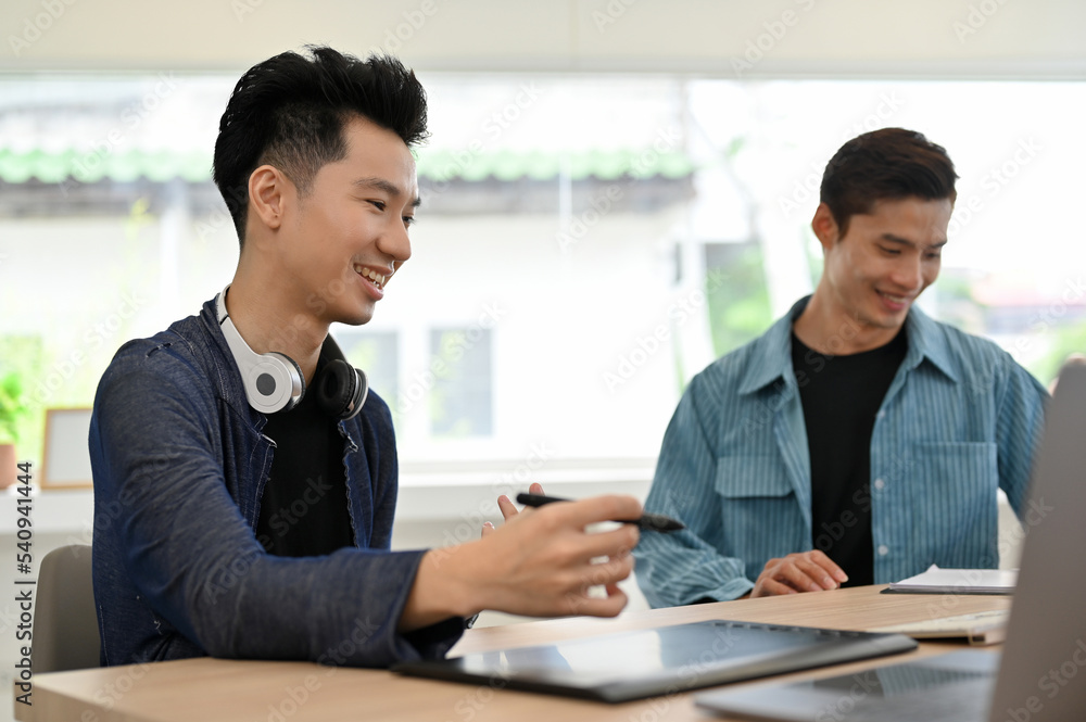 Two smart millennial Asian male web developers discussing and working together Two smart millennial Asian male web developers discussing and working together