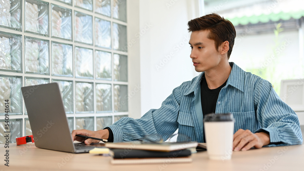 Smart Asian businessman or male office worker working on his tasks on laptop in the office. Smart Asian businessman or male office worker working on his tasks on laptop in the office.