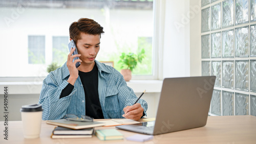 Handsome Asian male college student or freelancer remote working at the coffee shop